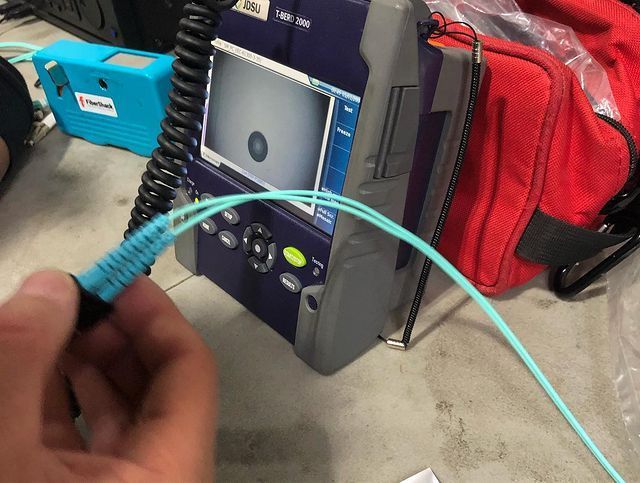 A person is plugging a fiber optic cable into a device