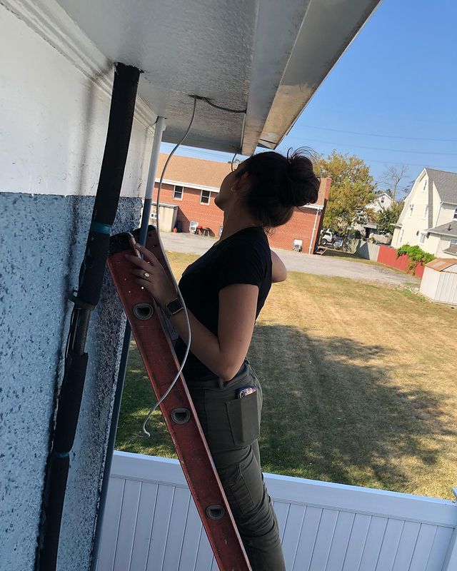 A woman is standing on a ladder on the side of a building