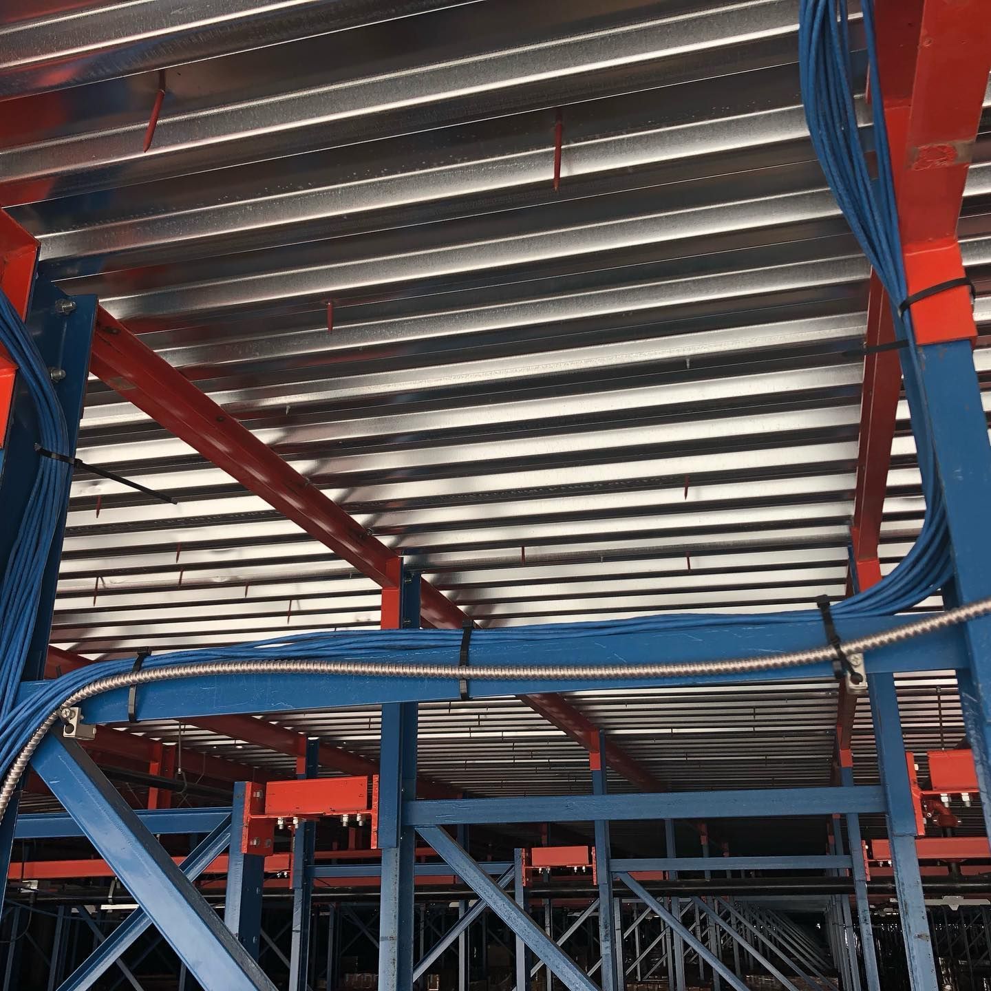 The ceiling of a building with a lot of wires hanging from it