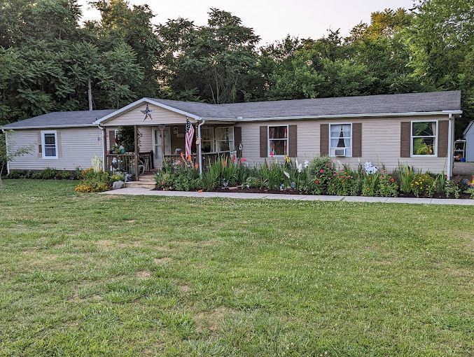 A mobile home with a large lawn in front of it.