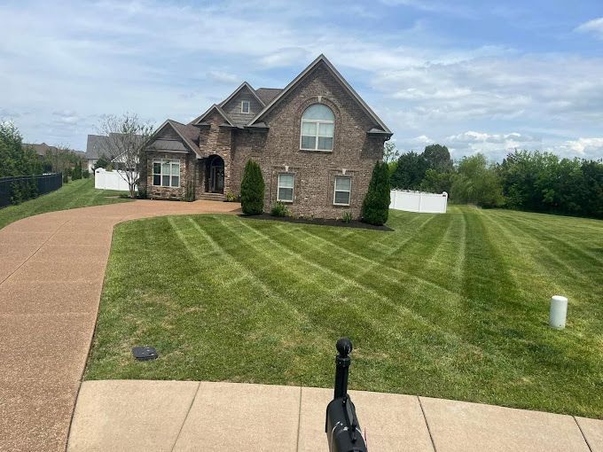 A large brick house with a lush green lawn in front of it.