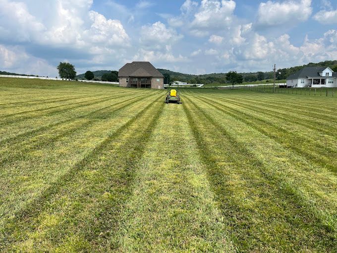 A person is riding a lawn mower through a grassy field.
