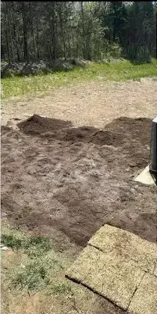A pile of dirt is sitting on top of a lush green field.