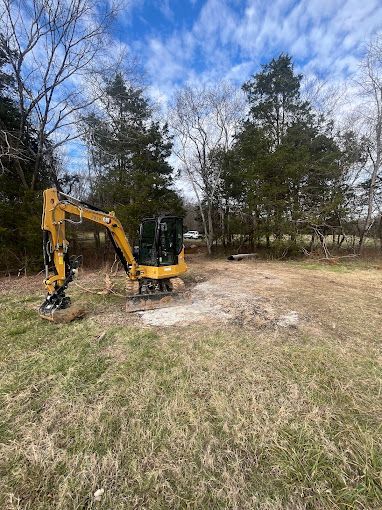 A yellow excavator is sitting in the middle of a field.