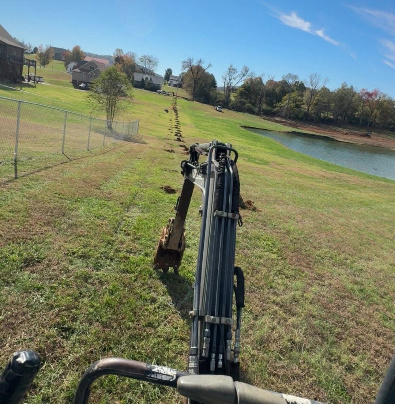 Red brick house with stone accents, cloudy sky. Green bushes and brown gravel in front.