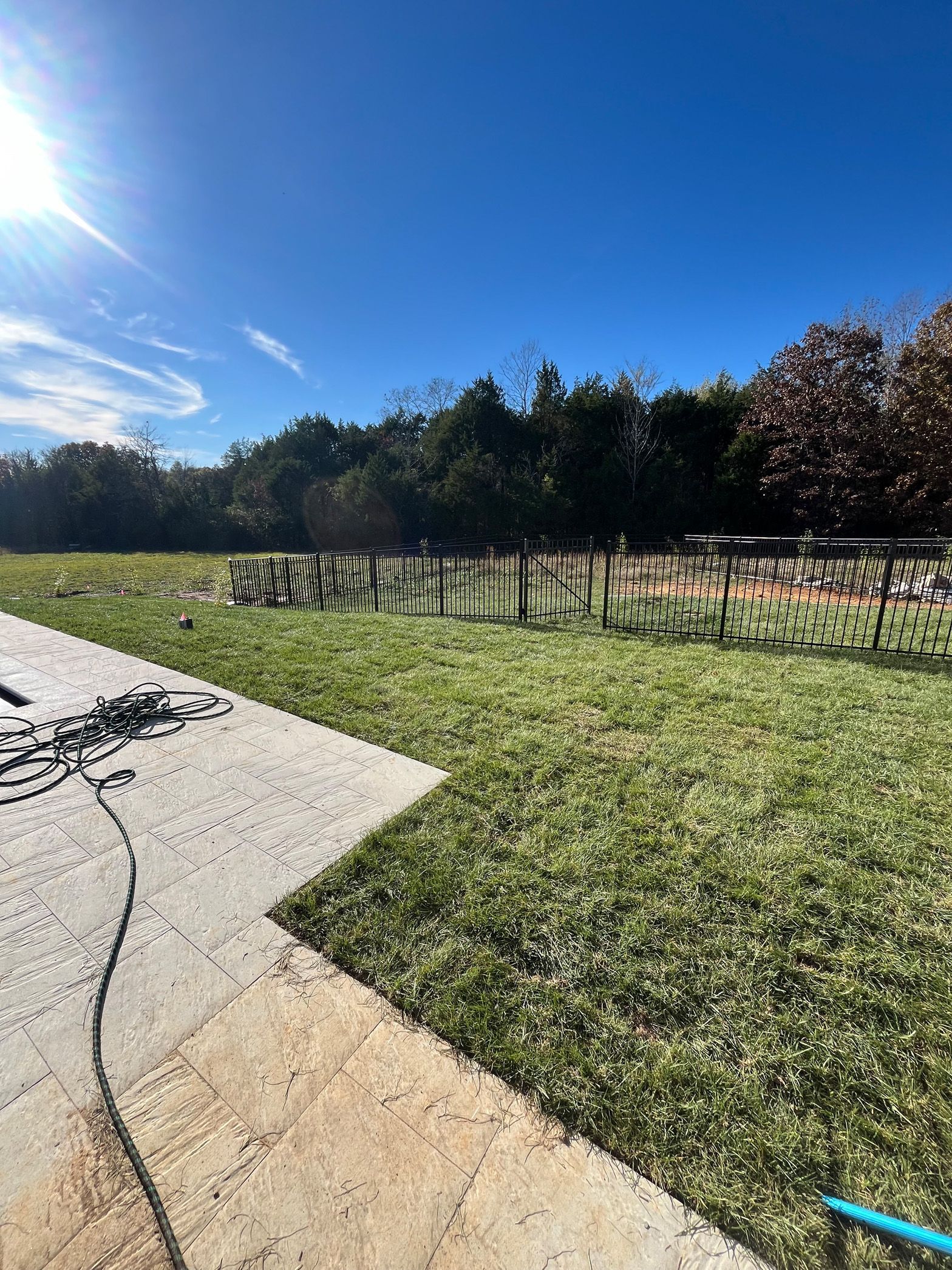 A concrete walkway leading to a grassy field with trees in the background.