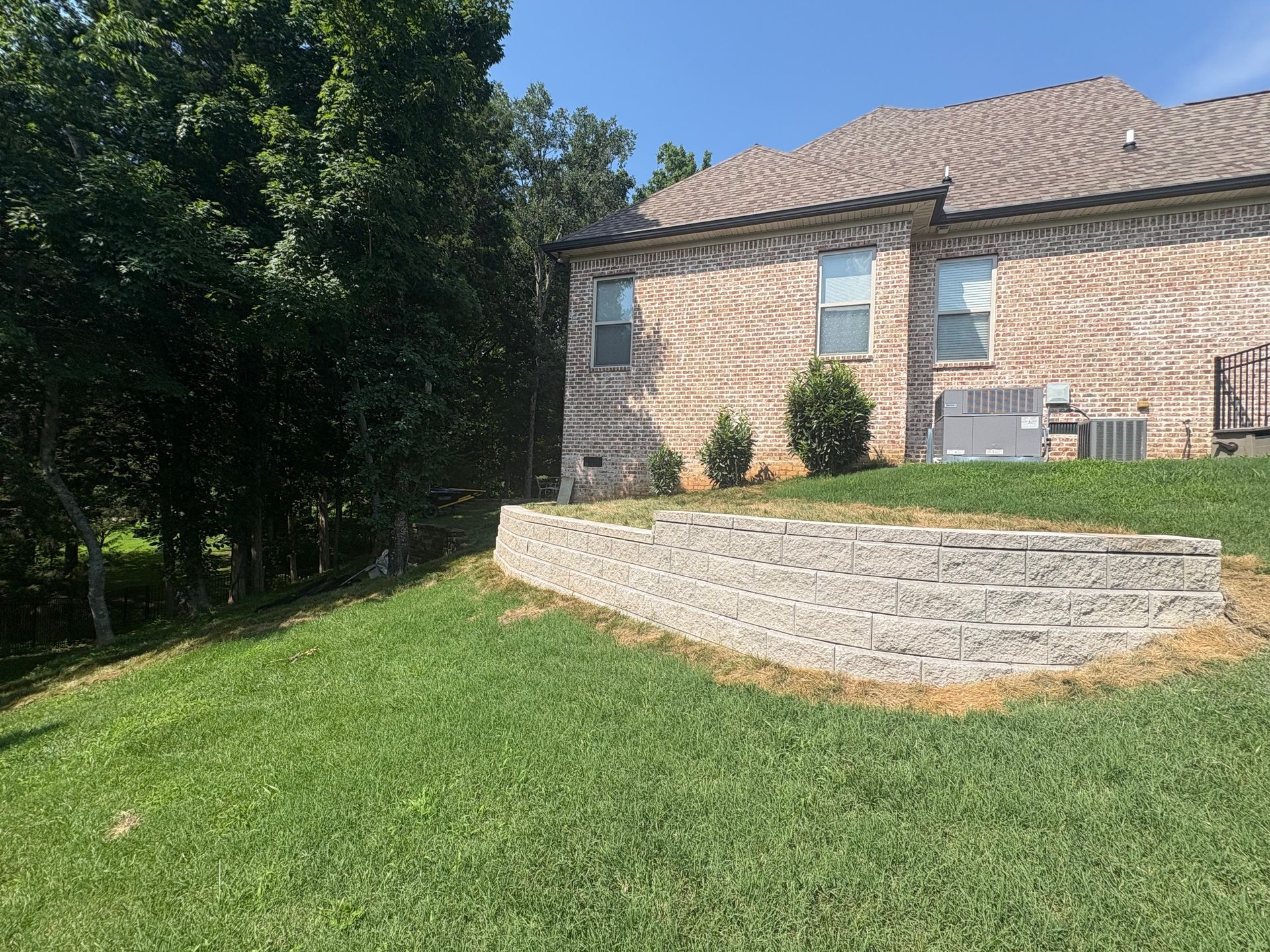 A large brick house with a stone wall in front of it.