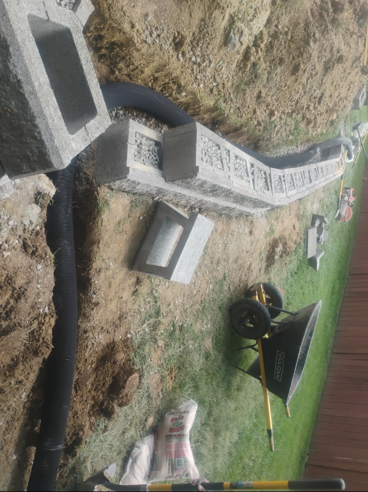A wheelbarrow is sitting in the dirt next to a concrete block.