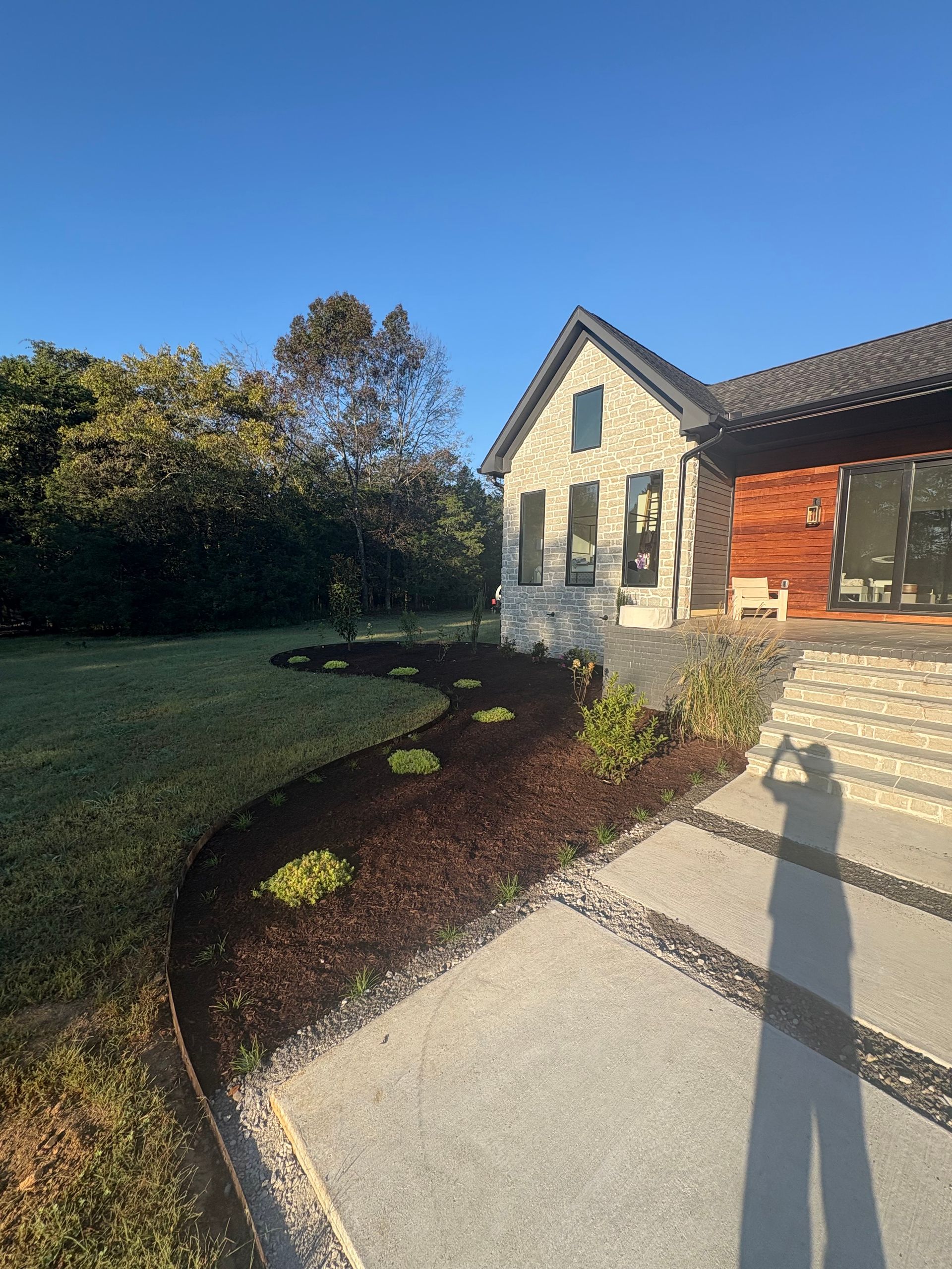 White house with black roof on green grass under a bright blue sky.