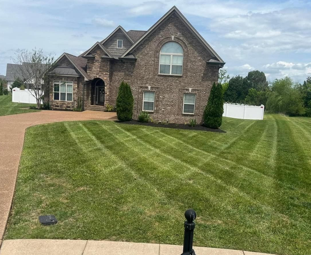 A large grassy field with a barn in the background on a sunny day.