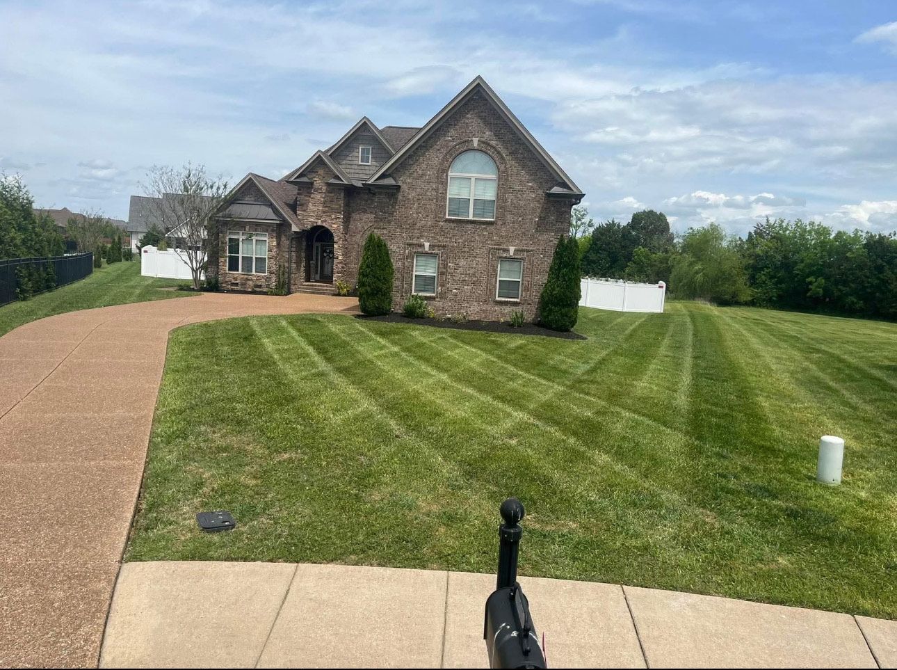 A lush green lawn is being mowed in front of a house.