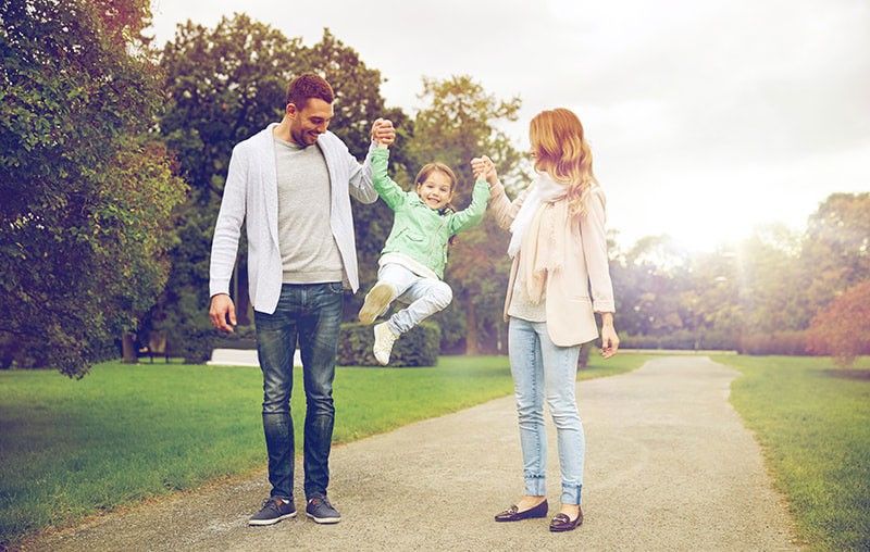 A family is walking down a path in a park.