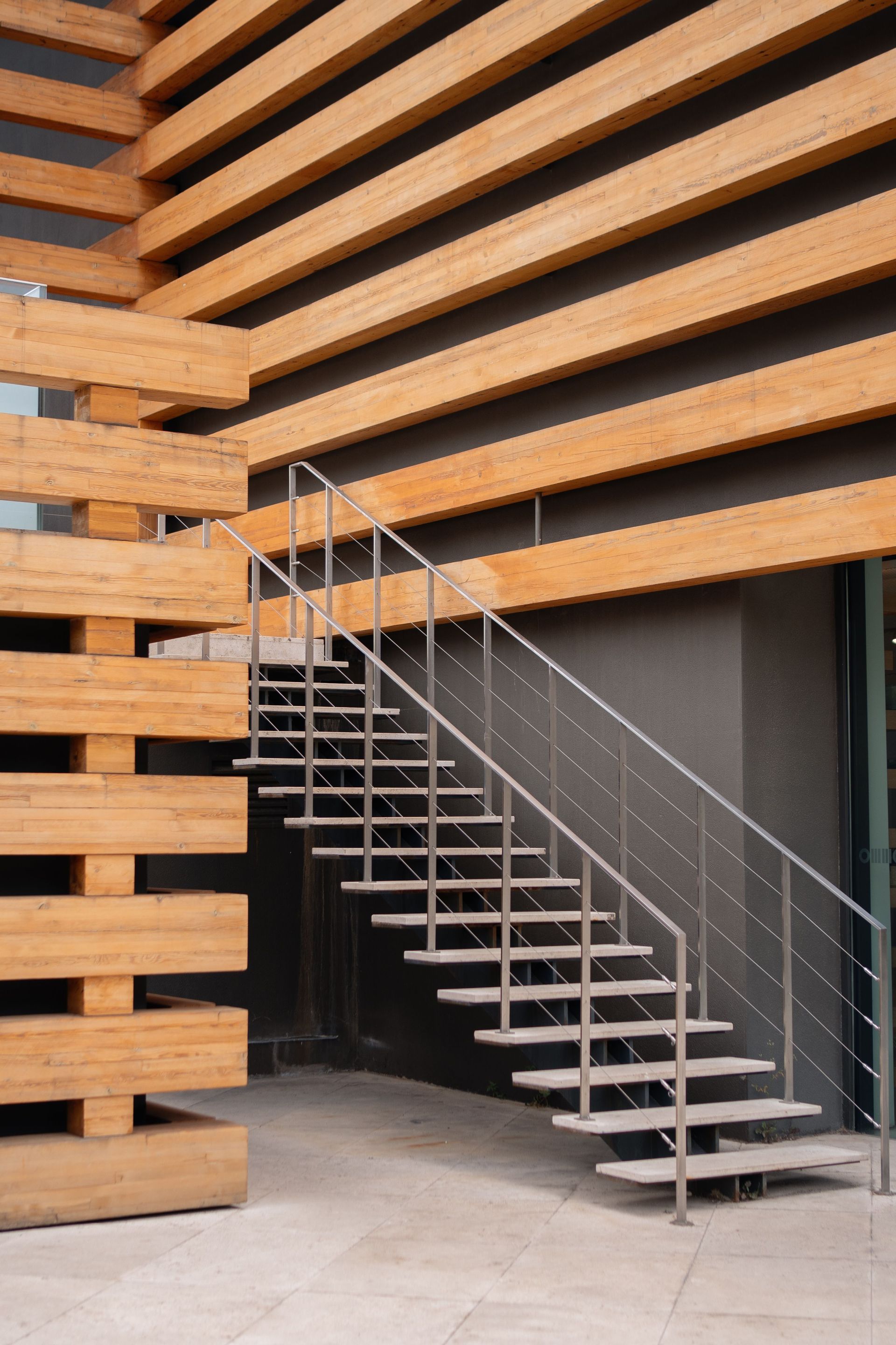 Modern building exterior with wooden slats and a metal staircase leading to a dark entrance