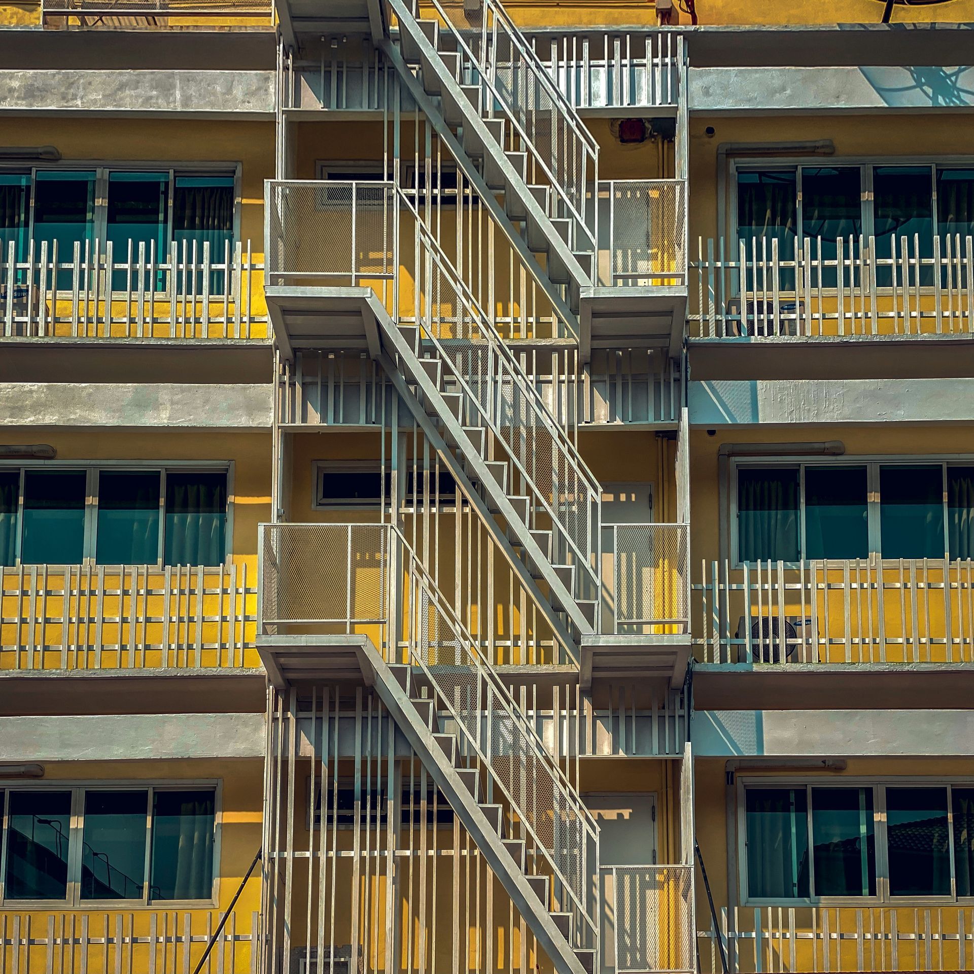 Exterior of an apartment building with metal fire escape stairs and yellow railings