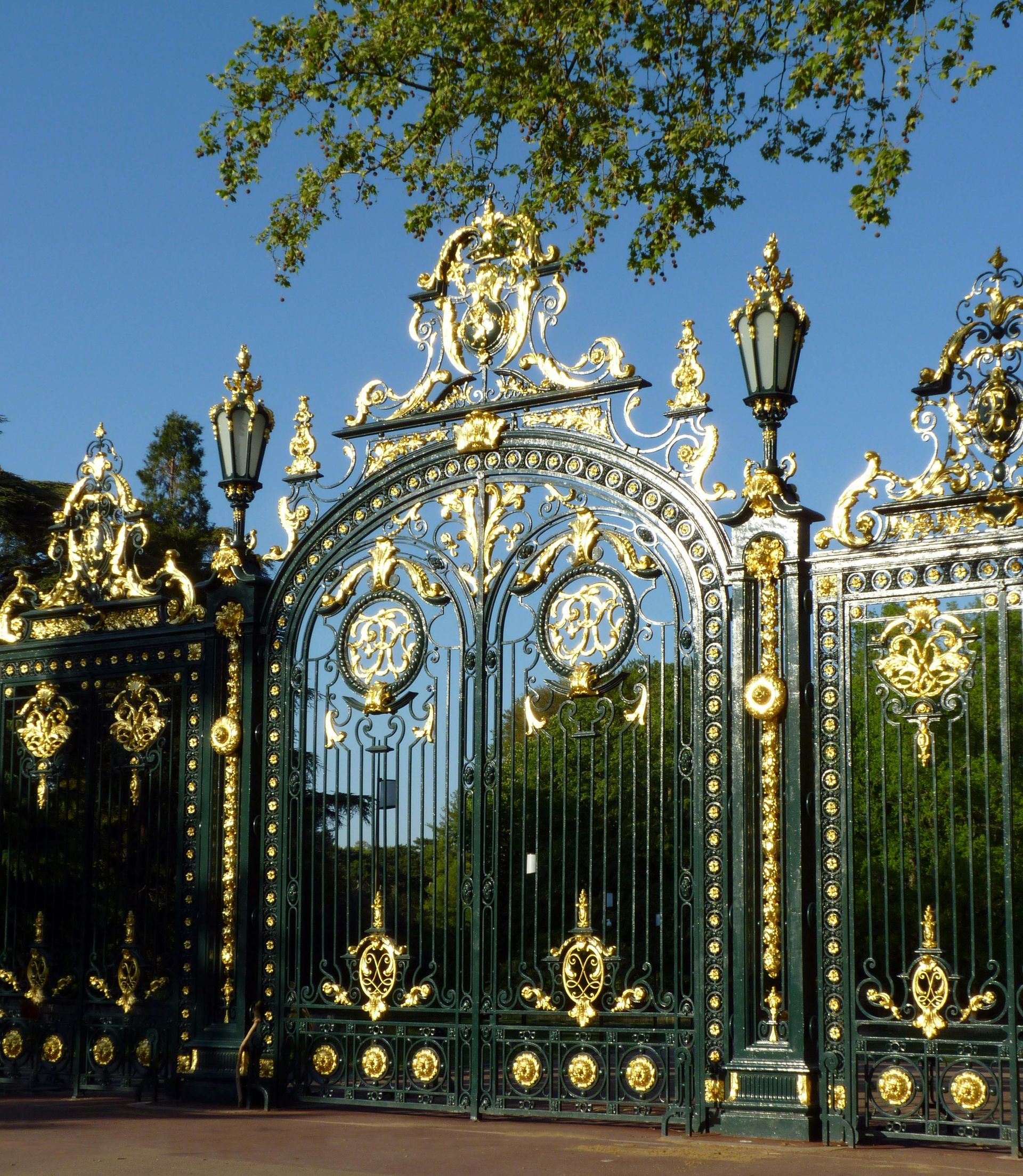 Ornate gold and green wrought-iron gate in Sunnyvale beneath tree branches