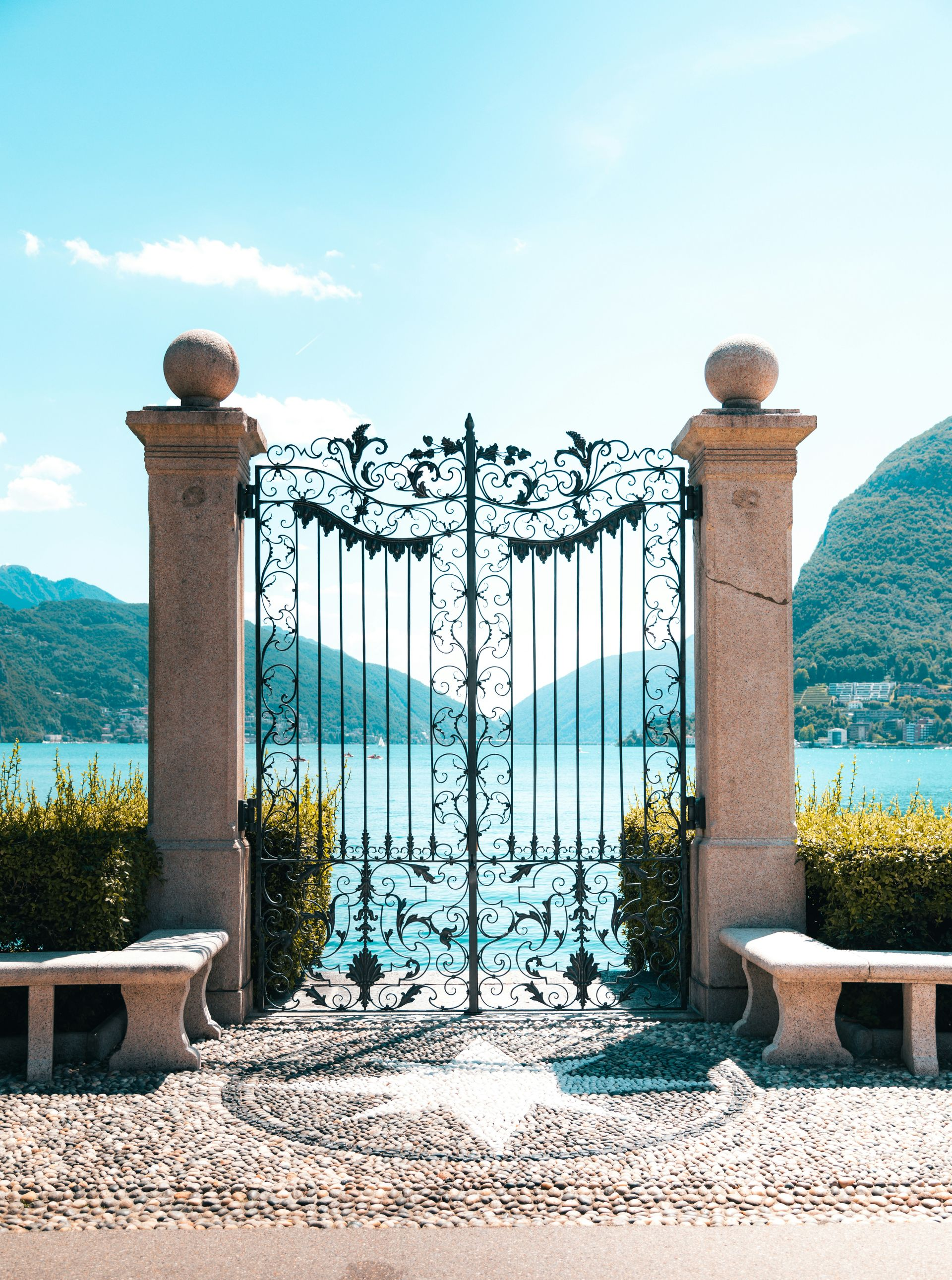 Stone gate opening to a bright lake in Los Altos  and mountains under a clear sky