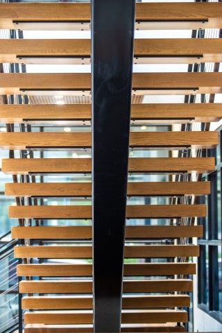 Wooden slat staircase accented with black handrails