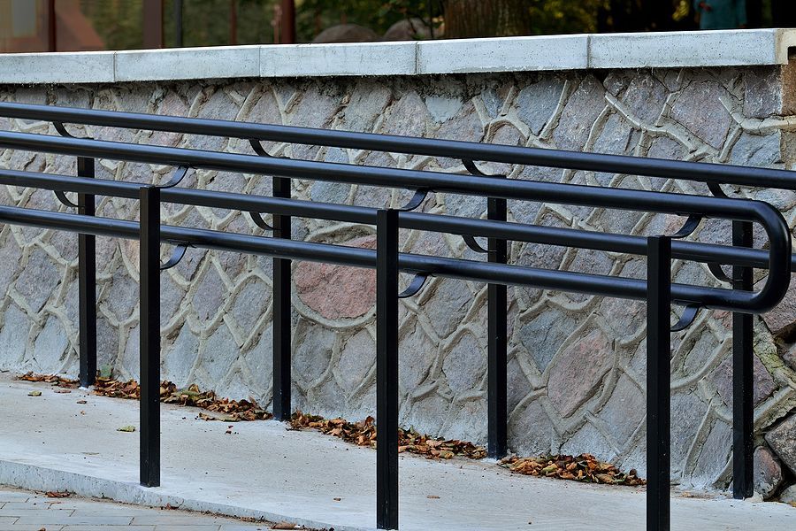 Black metal rails along a textured wall with leaves on the walkway