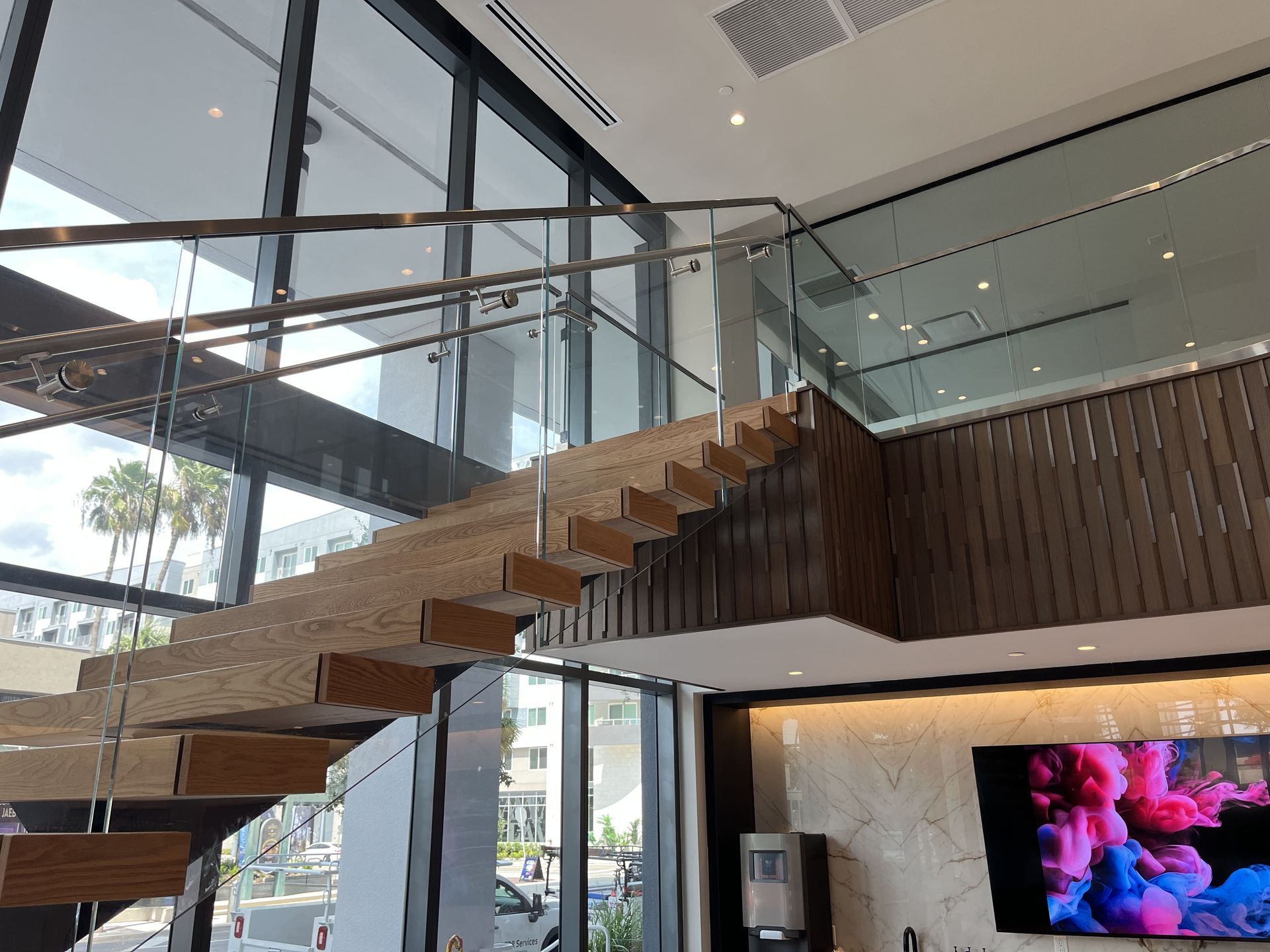 Sleek glass-railed stairs with TV mounted above