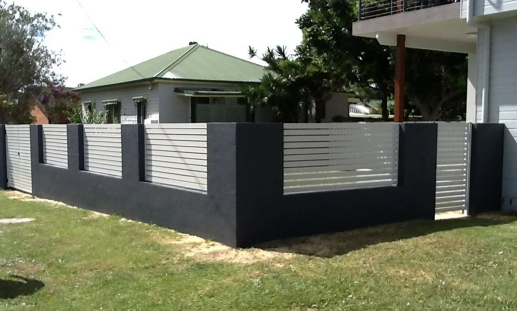 A Black and White Fence in Front of A House — Topline Aluminium Forster Pty Ltd in Hallidays Point, NSW