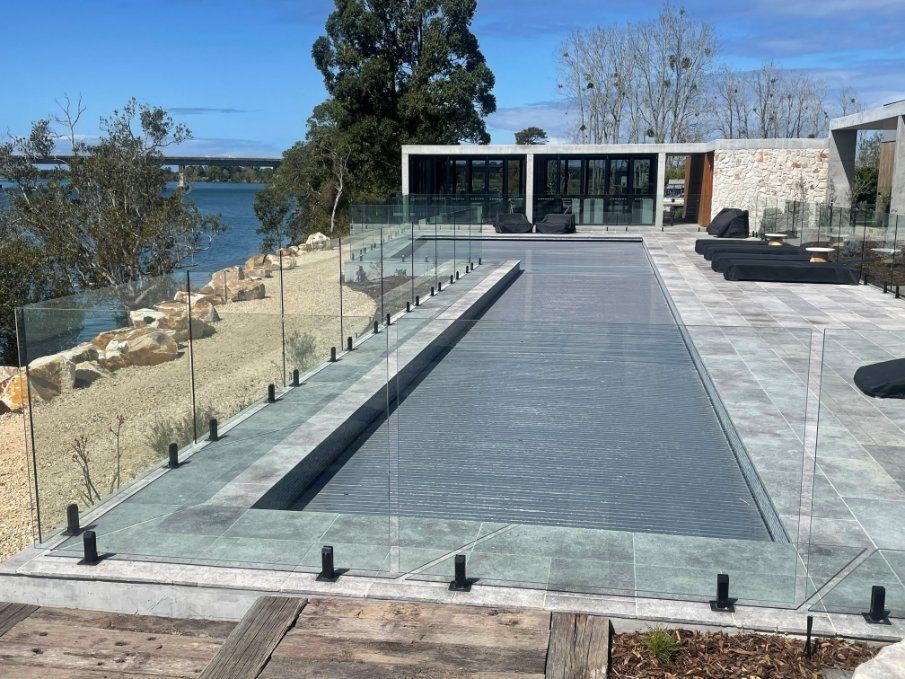 A Large Swimming Pool Is Surrounded by A Glass Fence — Topline Aluminium Forster Pty Ltd in Forster, NSW