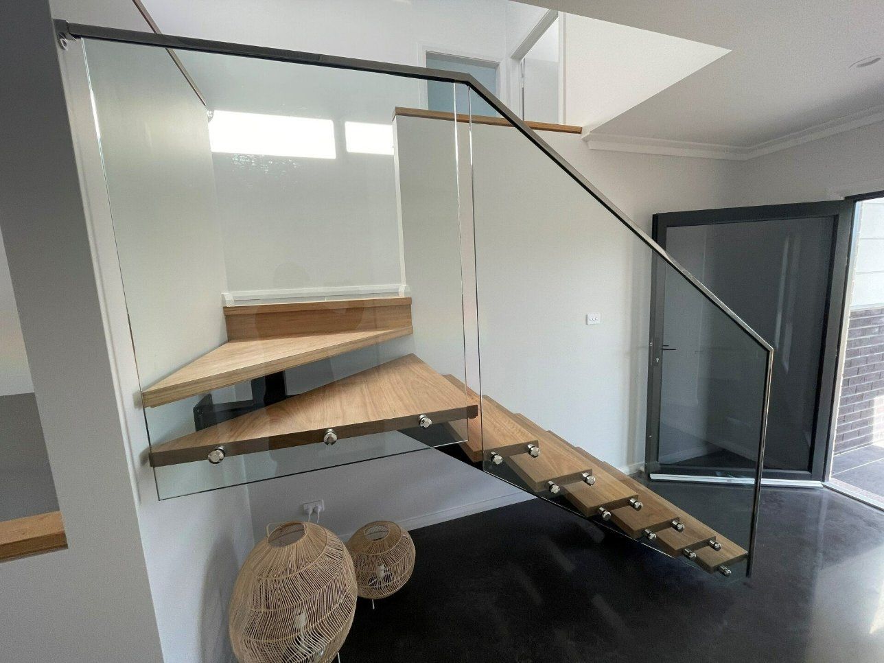 A Wooden Staircase with A Glass Railing in A Room — Topline Aluminium Forster Pty Ltd in Hallidays Point, NSW