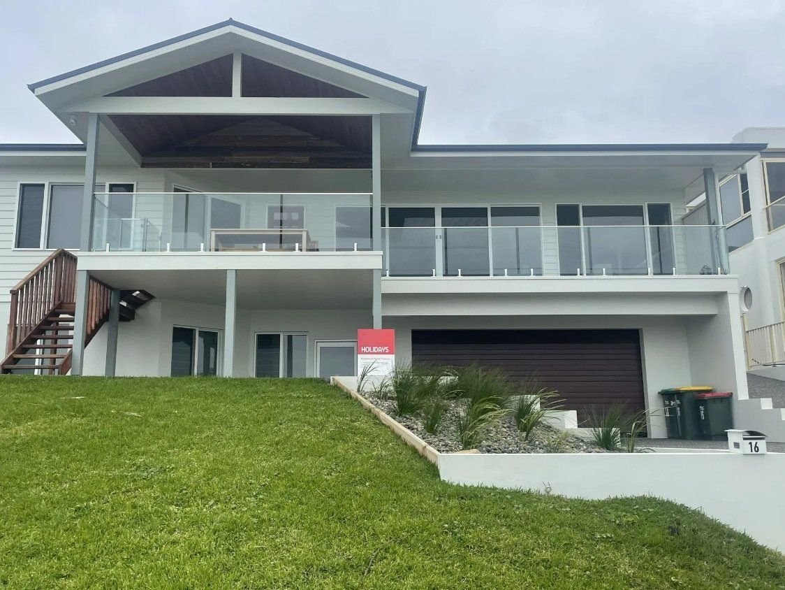 A Large White House with A for Sale Sign in Front of It — Topline Aluminium Forster Pty Ltd in Harrington, NSW