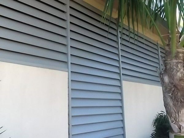 A Fence with A Palm Tree in Front of It — Topline Aluminium Forster Pty Ltd in Forster, NSW