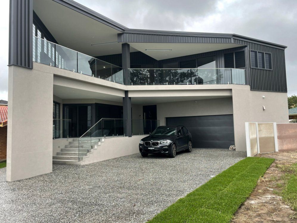 A Black Car Is Parked in Front of A Large House — Topline Aluminium Forster Pty Ltd in Forster, NSW
