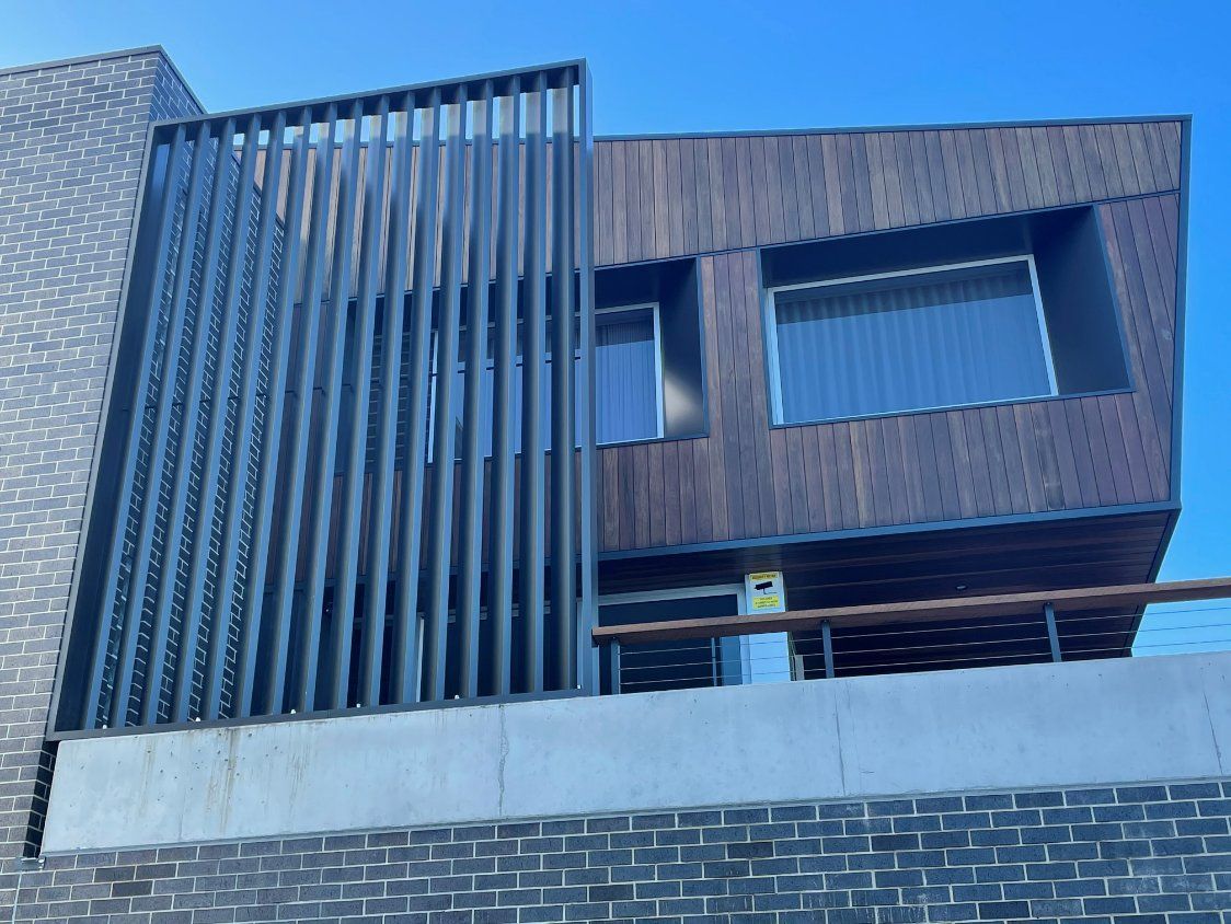 A modern house with a brick wall and a wooden facade. — Topline Aluminium Forster Pty Ltd in Forster, NSW