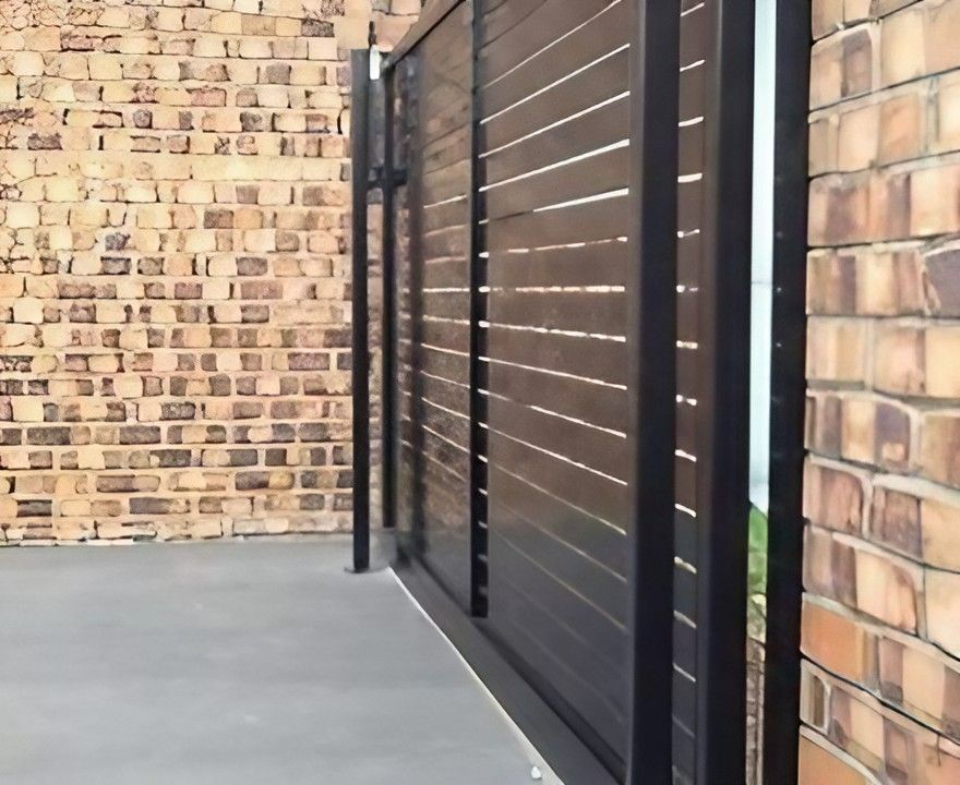 A Brick Wall with A Wooden Fence in Front of It — Topline Aluminium Forster Pty Ltd in Taree, NSW