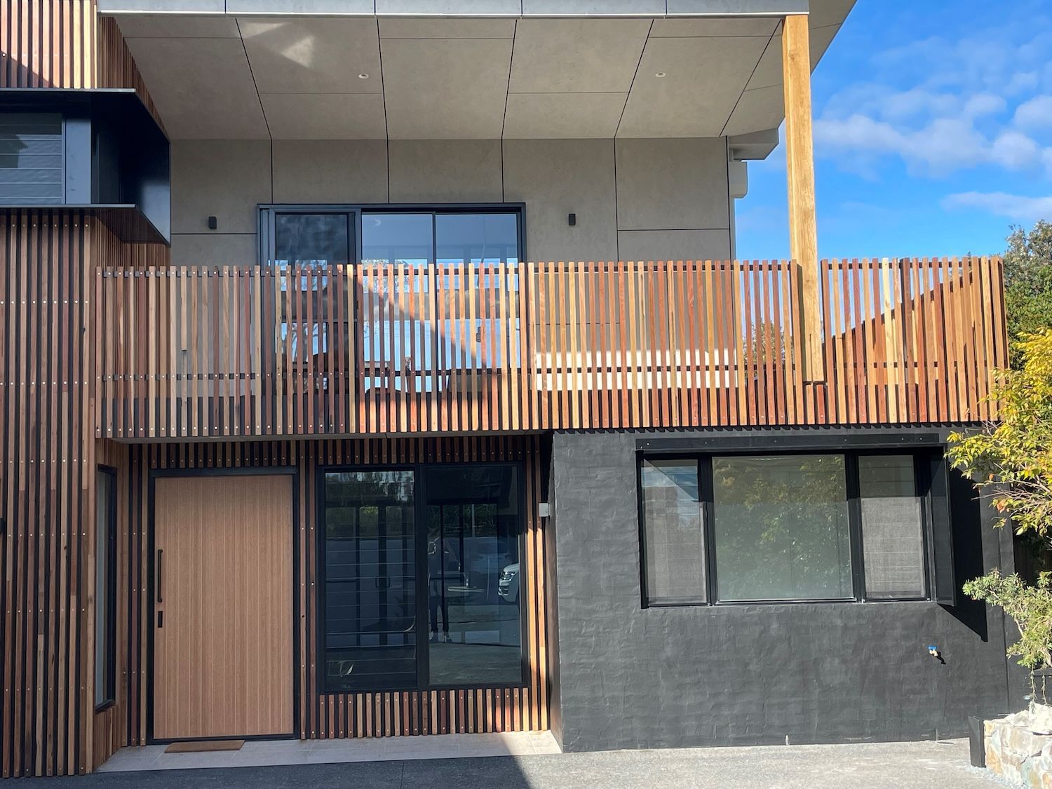 A Large White House with A Brown Garage Door and Stairs Leading up To It — Topline Aluminium Forster Pty Ltd in Forster, NSW