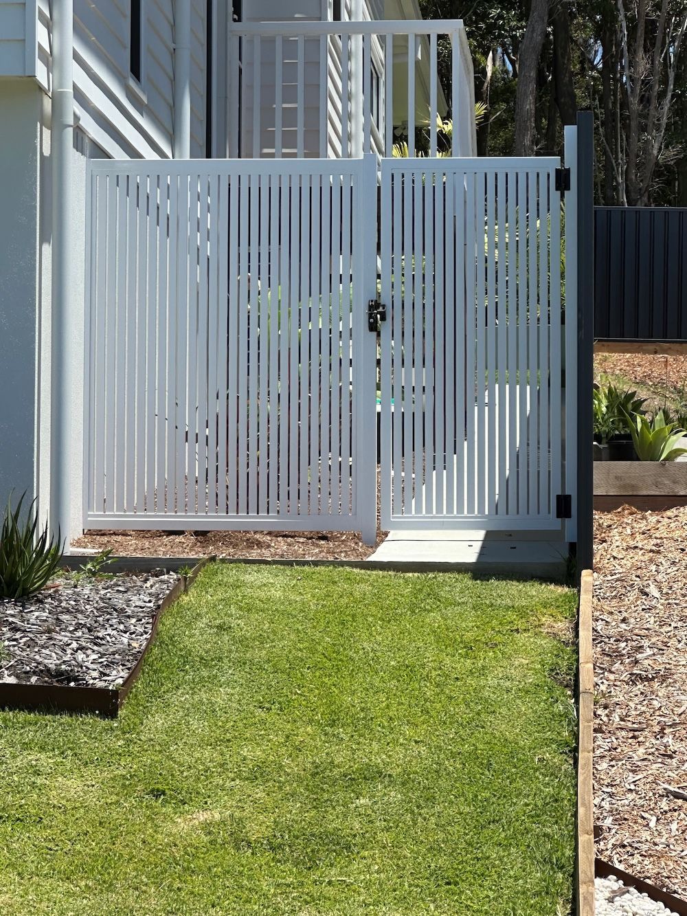 A Black Gate Is Sitting on The Side of A Road Next to A Grassy Field — Topline Aluminium Forster Pty Ltd in Forster, NSW