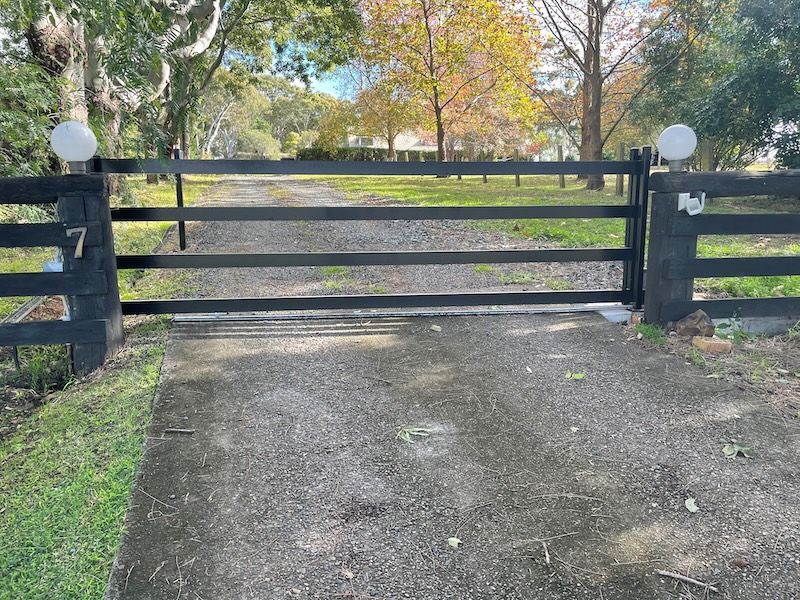 A White Sliding Gate Is Sitting in Front of A House — Topline Aluminium Forster Pty Ltd in Forster, NSW