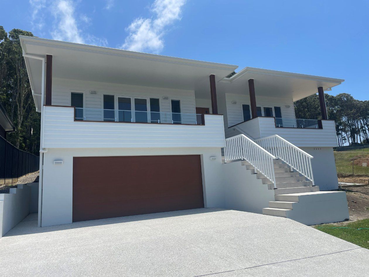 White House with A Brown Garage Door and Stairs — Topline Aluminium Forster Pty Ltd in Smiths Lake, NSW