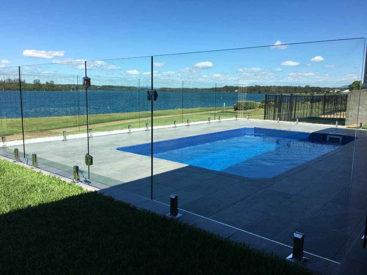 Swimming Pool Surrounded by A Glass Fence — Topline Aluminium Forster Pty Ltd in Hallidays Point, NSW