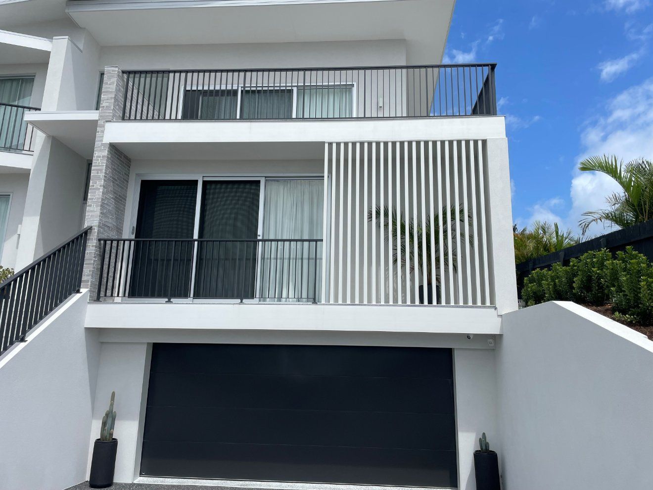A White House with A Black Garage Door and A Balcony — Topline Aluminium Forster Pty Ltd in Tuncurry, NSW