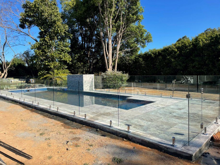 A Large Swimming Pool with A Glass Fence Around It — Topline Aluminium Forster Pty Ltd in Tuncurry, NSW
