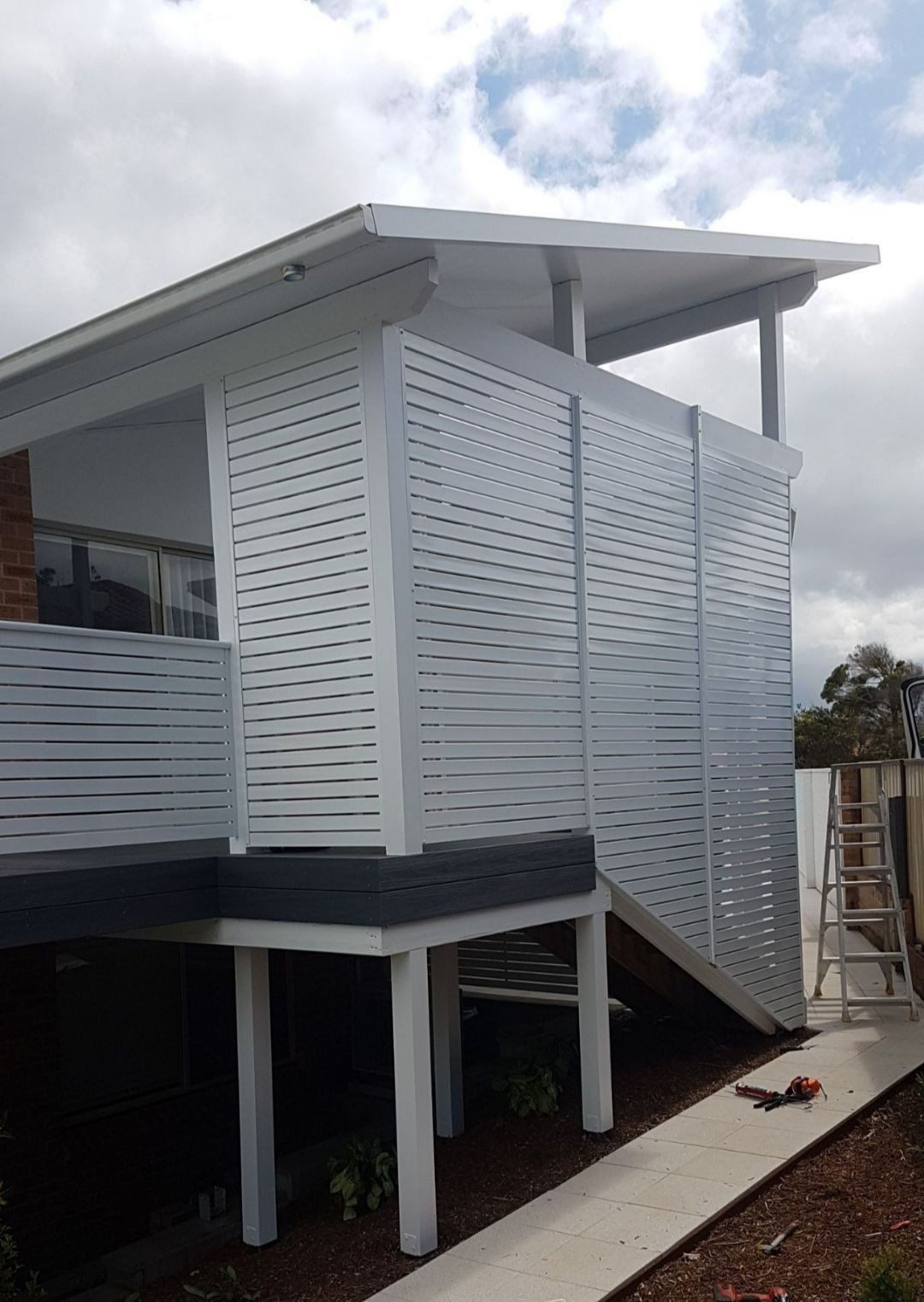 A Fence with A House in The Background Is Surrounded by Grass — Topline Aluminium Forster Pty Ltd in Tuncurry, NSW