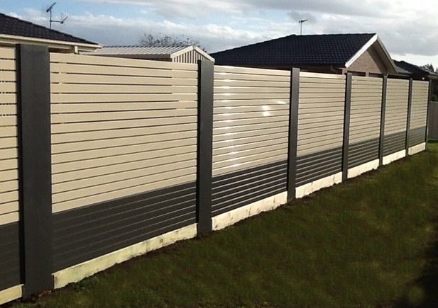A Fence with A House in The Background Is Surrounded by Grass — Topline Aluminium Forster Pty Ltd in Harrington, NSW