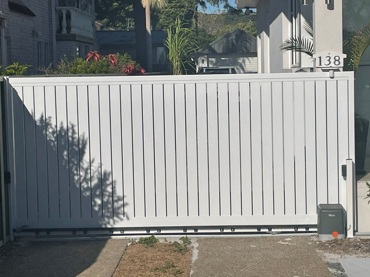 A White Sliding Gate Is Sitting in Front of A House — Topline Aluminium Forster Pty Ltd in Harrington, NSW