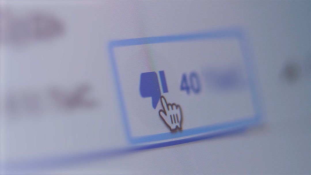 A computer screen with a thumbs down button and a hand pointing at it.