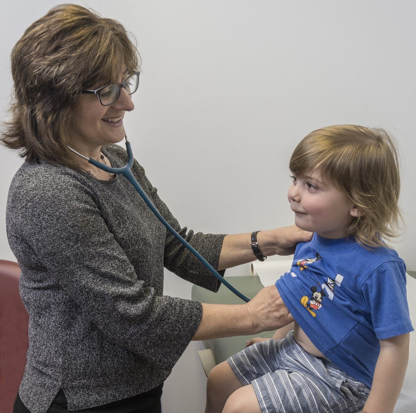 A woman is listening to a child 's heart with a stethoscope
