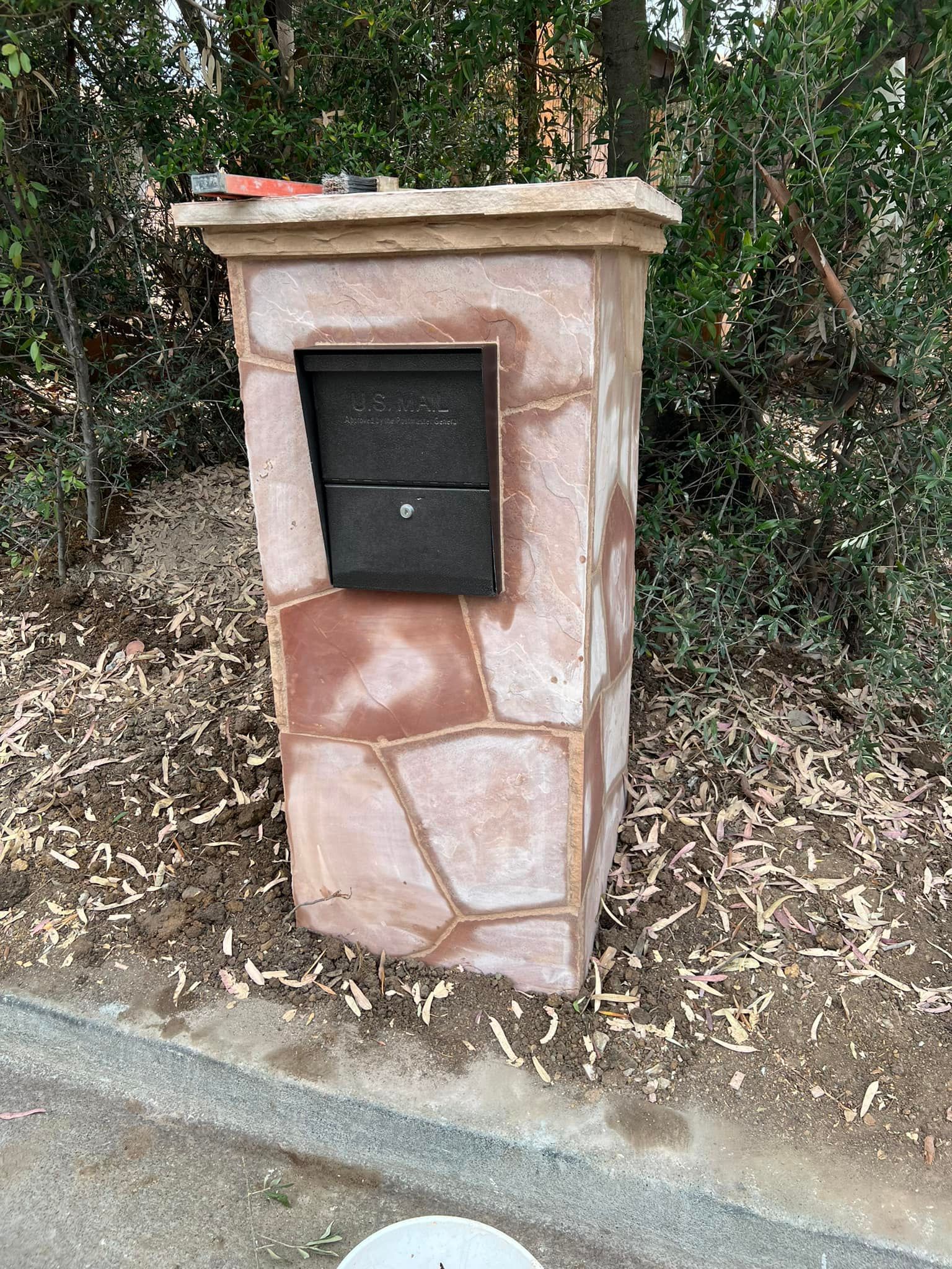 A mailbox is sitting on top of a stone pillar.