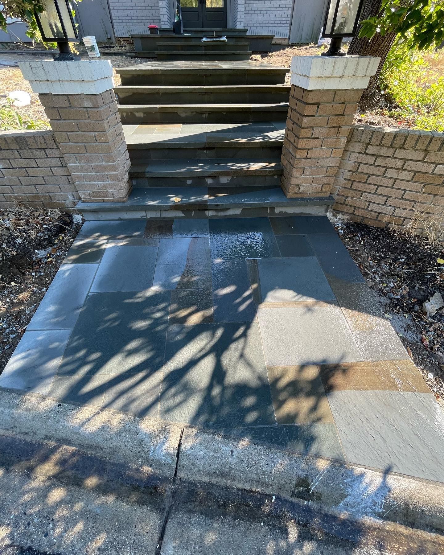 A stone walkway leading to a house with stairs and a brick wall.