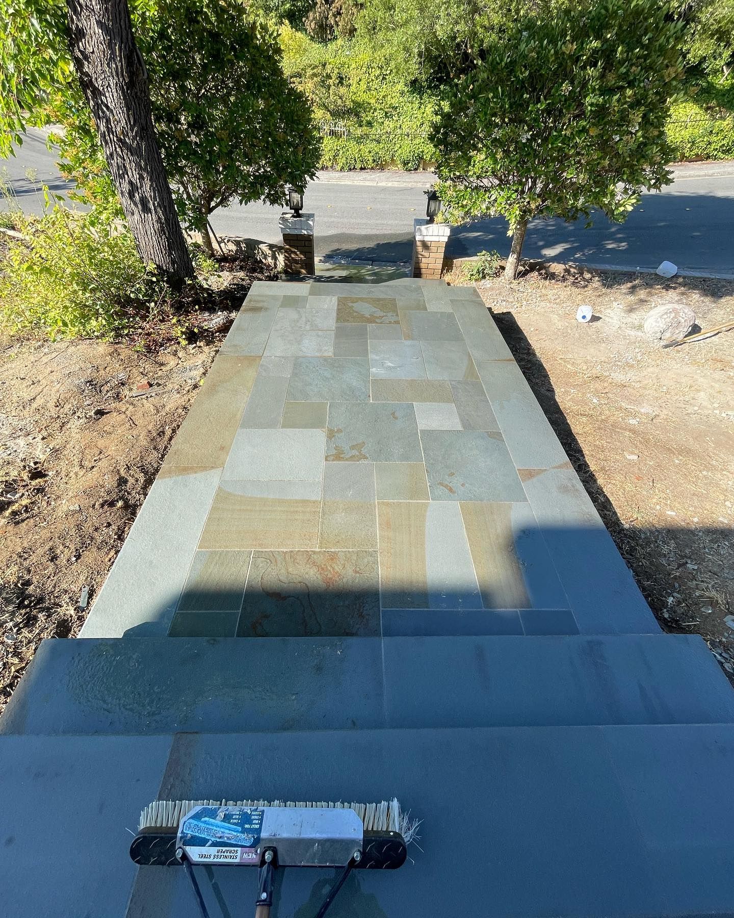 A broom is sitting on top of a stone walkway.