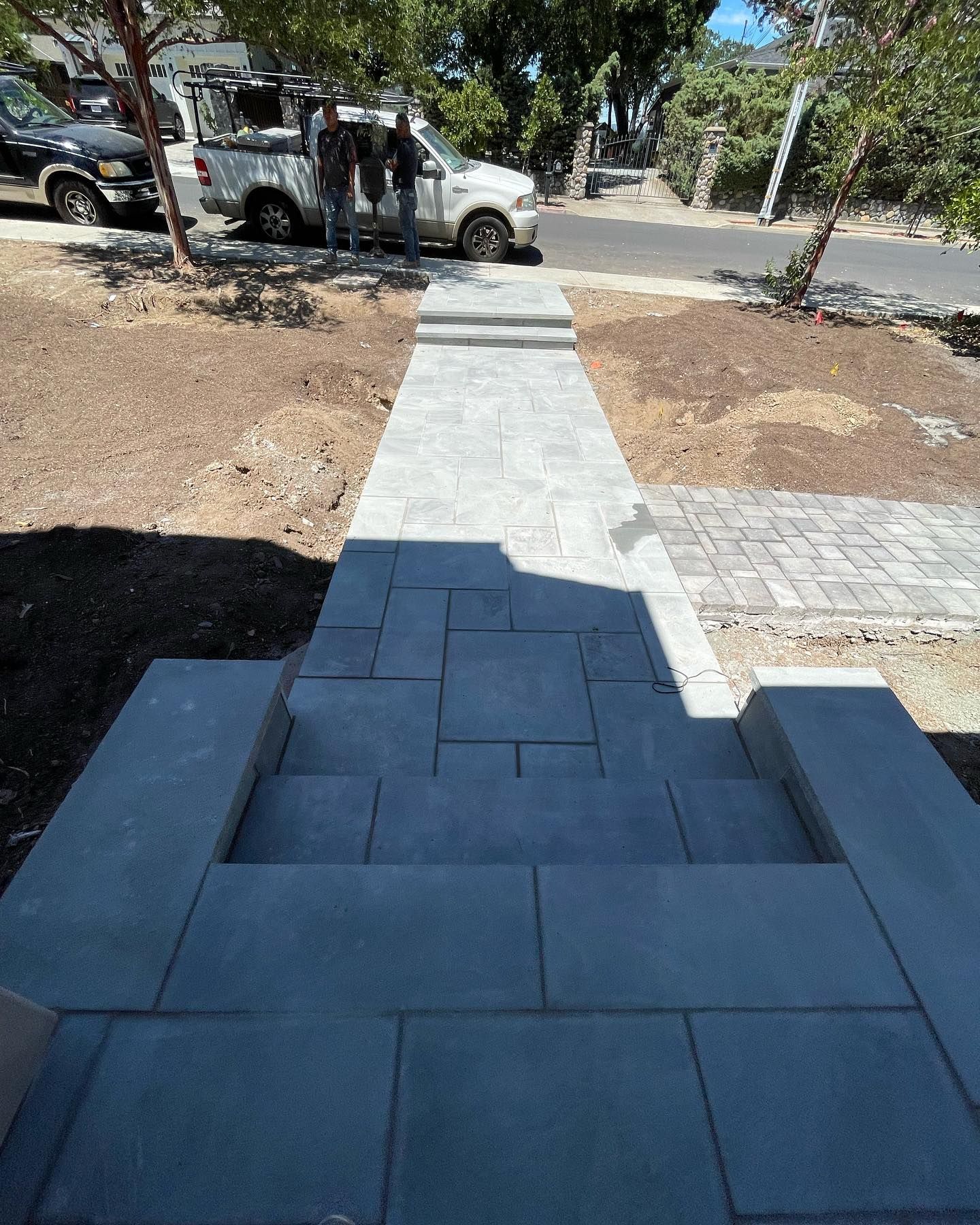 A white truck is parked on the side of the road next to a sidewalk