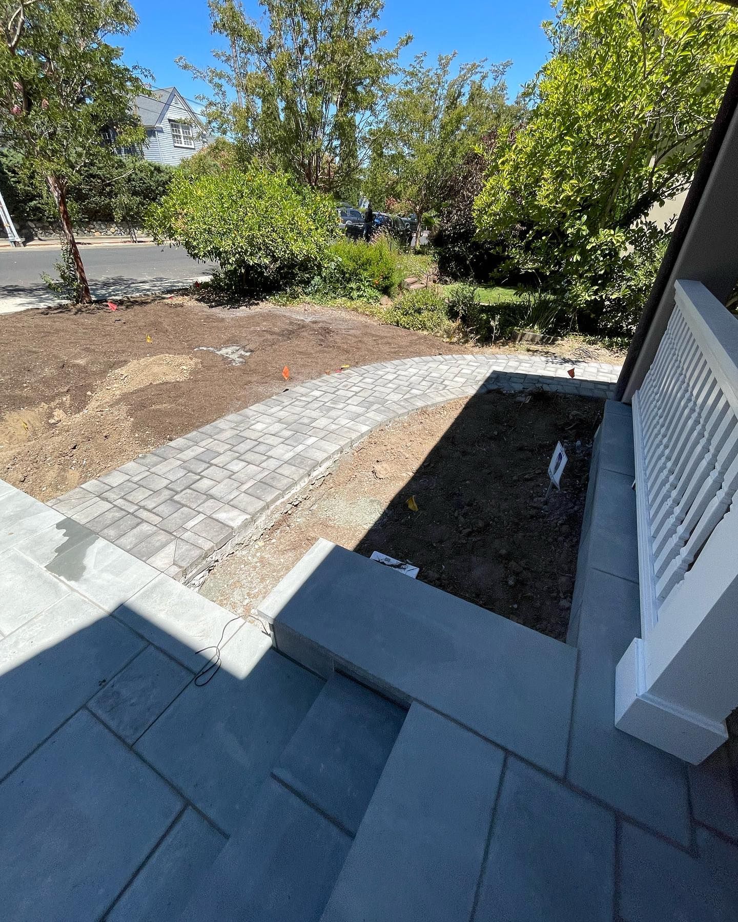 A brick walkway leading to a house with a white railing