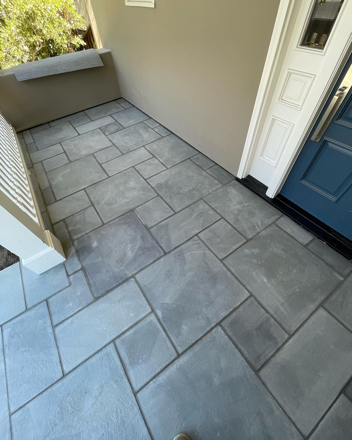 A porch with a blue door and a gray tile floor.