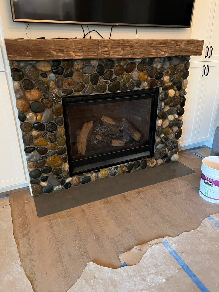 A fireplace made of rocks in a living room with a flat screen tv above it.